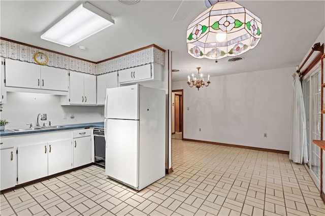 kitchen with an inviting chandelier, white cabinets, white refrigerator, and sink