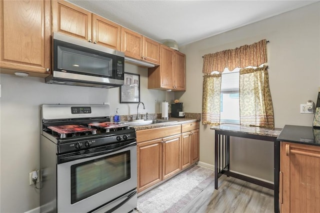 kitchen with sink, appliances with stainless steel finishes, and light hardwood / wood-style flooring