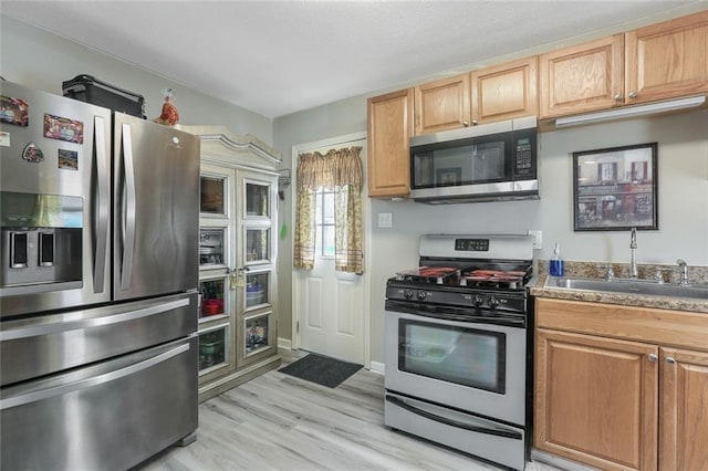 kitchen with light brown cabinets, sink, light wood-type flooring, and stainless steel appliances