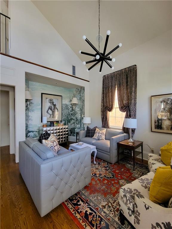 living room with hardwood / wood-style floors, an inviting chandelier, and high vaulted ceiling