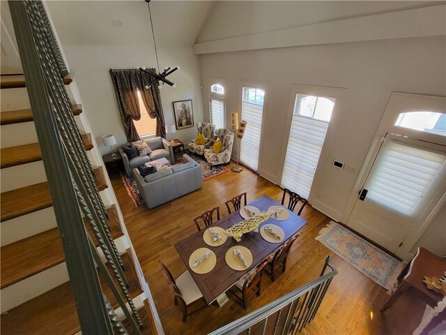 dining space with high vaulted ceiling and wood-type flooring