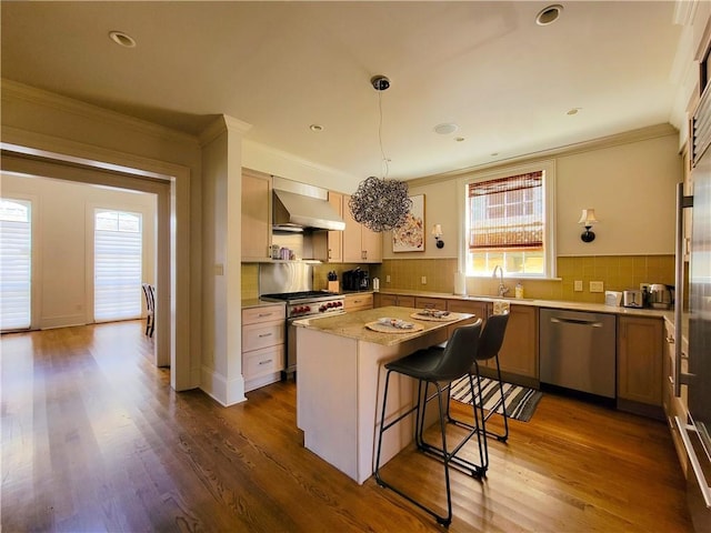 kitchen featuring hanging light fixtures, wall chimney exhaust hood, dark hardwood / wood-style floors, a kitchen island, and stainless steel appliances