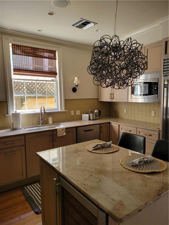 kitchen with light stone countertops, stainless steel appliances, crown molding, a chandelier, and light wood-type flooring