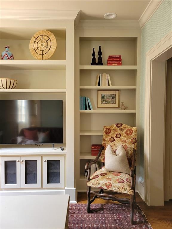 sitting room with hardwood / wood-style flooring, built in features, and ornamental molding