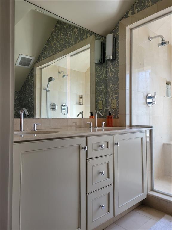 bathroom with tile patterned floors, vanity, vaulted ceiling, and walk in shower