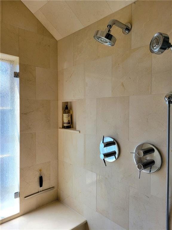 bathroom with lofted ceiling and tiled shower