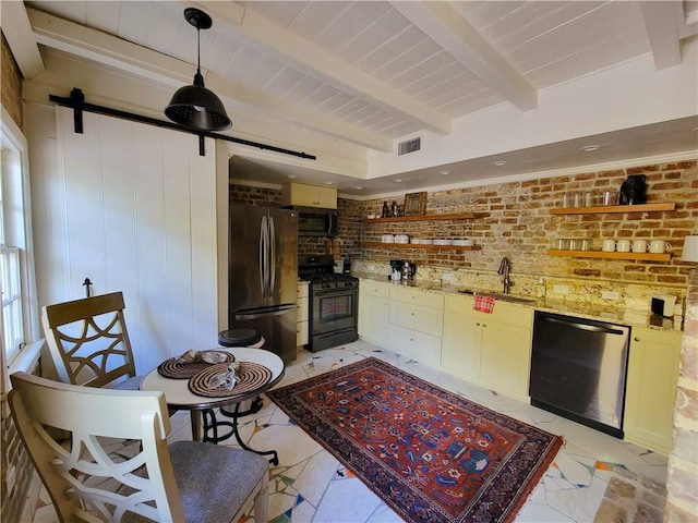 kitchen with a barn door, brick wall, sink, and appliances with stainless steel finishes