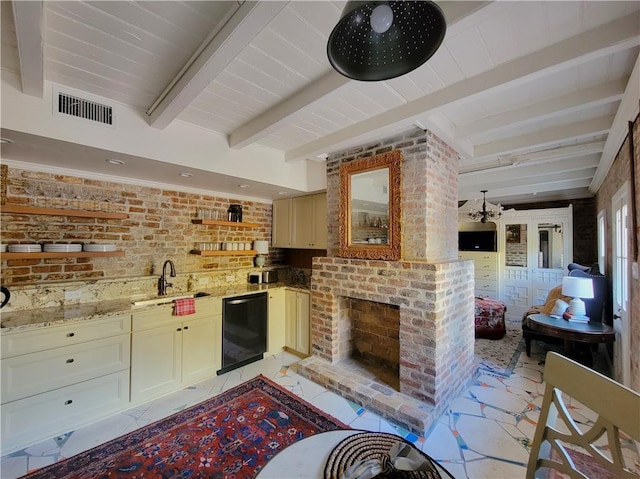 kitchen featuring light stone countertops, beam ceiling, sink, and brick wall