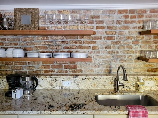 details with light stone counters, sink, and ornamental molding