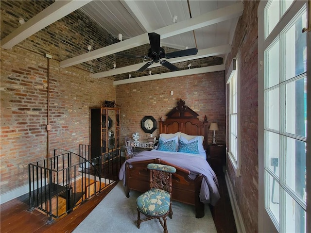 bedroom featuring brick wall, ceiling fan, beam ceiling, hardwood / wood-style flooring, and a high ceiling