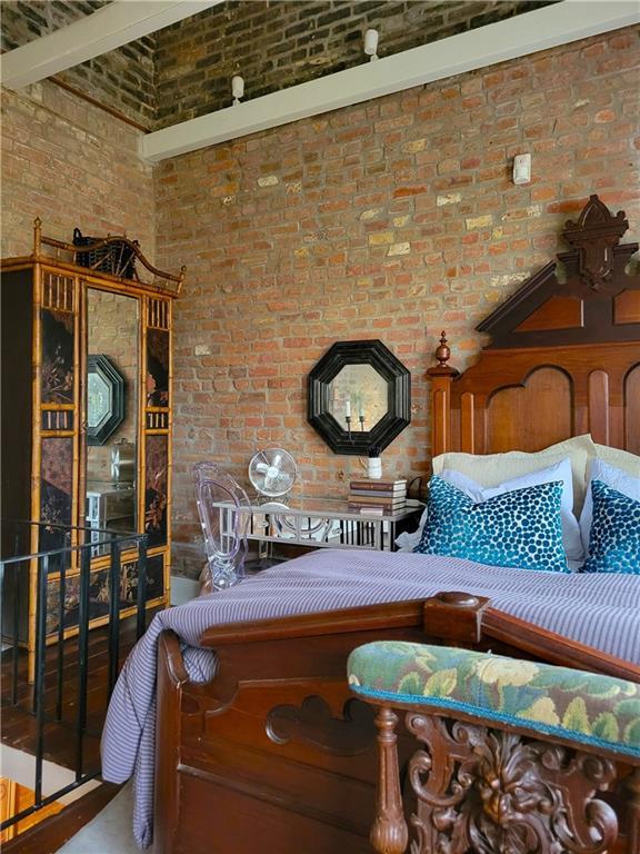 interior space featuring beamed ceiling, a high ceiling, and brick wall