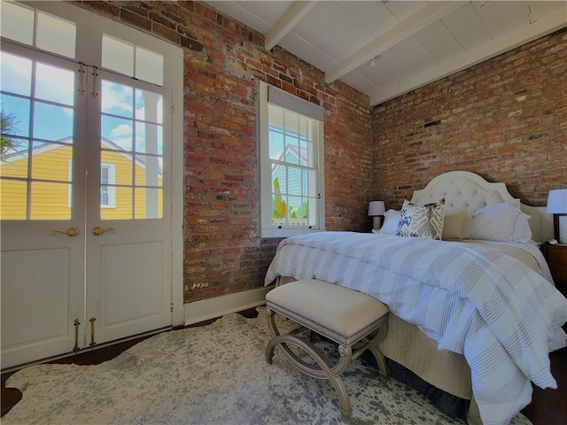 bedroom featuring beamed ceiling, multiple windows, and brick wall