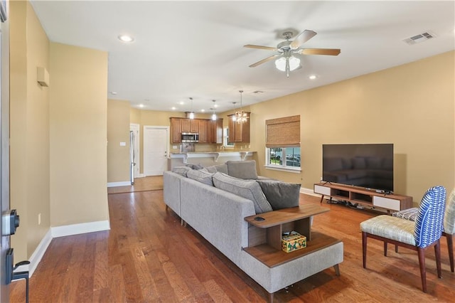 living room featuring ceiling fan with notable chandelier and hardwood / wood-style floors