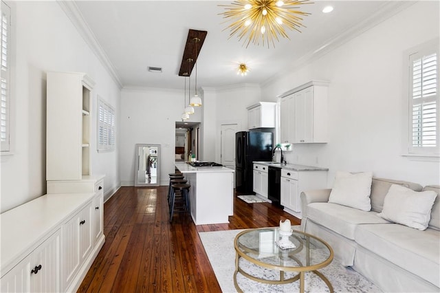 living room with crown molding, dark hardwood / wood-style flooring, sink, and a notable chandelier