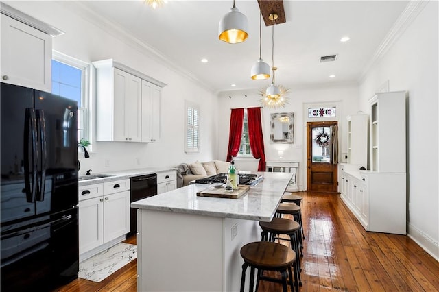 kitchen with white cabinets, a center island, dark hardwood / wood-style flooring, and black appliances