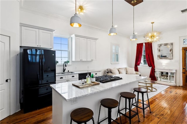 kitchen with black appliances, sink, pendant lighting, and dark wood-type flooring