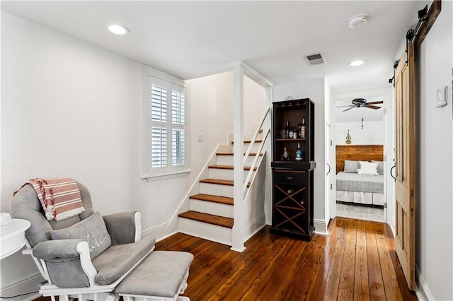 staircase with ceiling fan, hardwood / wood-style flooring, and a barn door