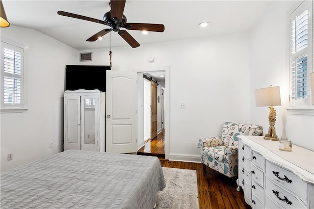 bedroom with ceiling fan, lofted ceiling, a barn door, and dark hardwood / wood-style flooring