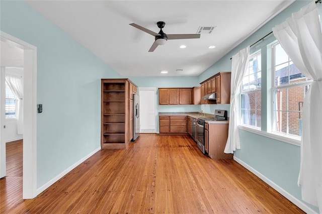 kitchen with ceiling fan, appliances with stainless steel finishes, plenty of natural light, and light hardwood / wood-style flooring