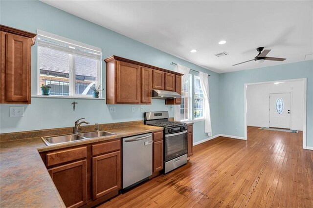 kitchen with appliances with stainless steel finishes, light wood-type flooring, sink, and ceiling fan