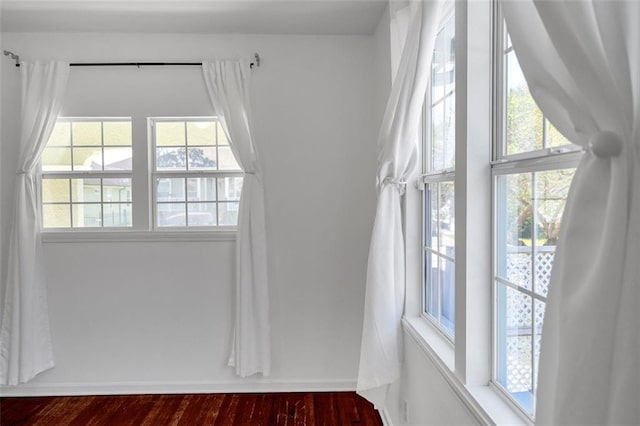 empty room with a wealth of natural light and dark hardwood / wood-style floors