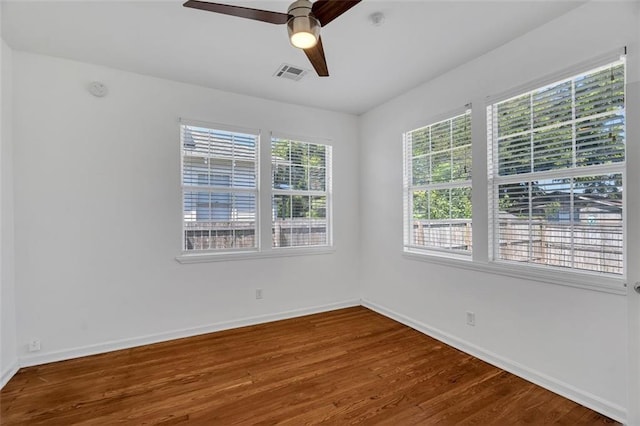 empty room featuring a wealth of natural light, ceiling fan, and hardwood / wood-style flooring