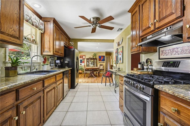 kitchen with stainless steel appliances, light wood-type flooring, sink, dark stone countertops, and ceiling fan