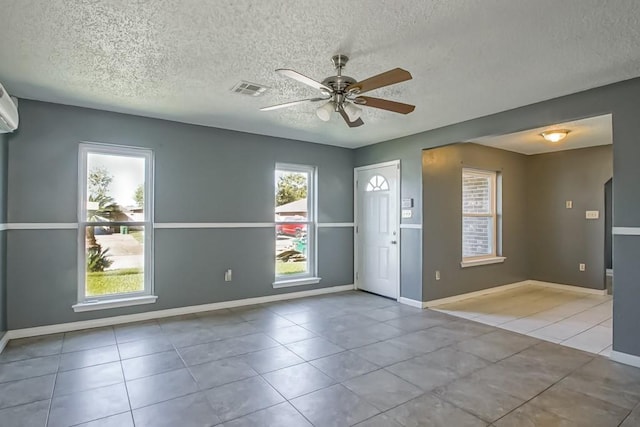 interior space with a textured ceiling, light tile patterned floors, and ceiling fan