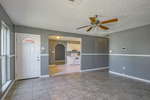 interior space with ceiling fan, a textured ceiling, and a healthy amount of sunlight