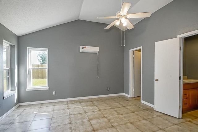 interior space with a wall unit AC, light tile patterned flooring, vaulted ceiling, ensuite bath, and ceiling fan