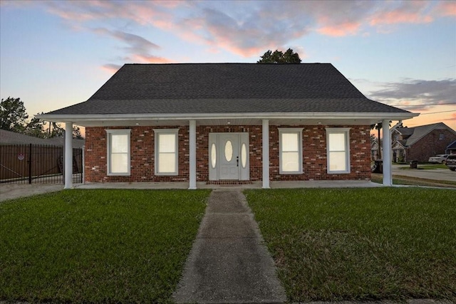 view of front of property with covered porch and a lawn