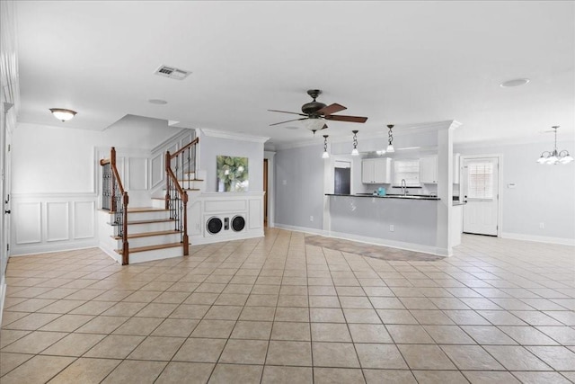 unfurnished living room with ornamental molding, light tile patterned flooring, sink, and ceiling fan with notable chandelier