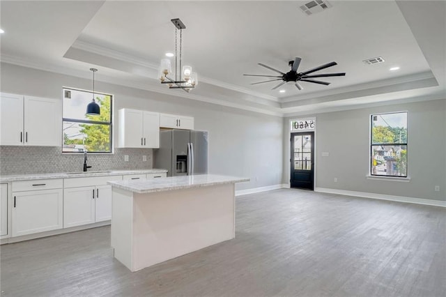 kitchen with stainless steel refrigerator with ice dispenser, a tray ceiling, and a center island