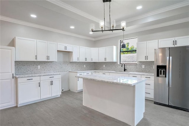 kitchen featuring hanging light fixtures, stainless steel refrigerator with ice dispenser, a kitchen island, and white cabinets