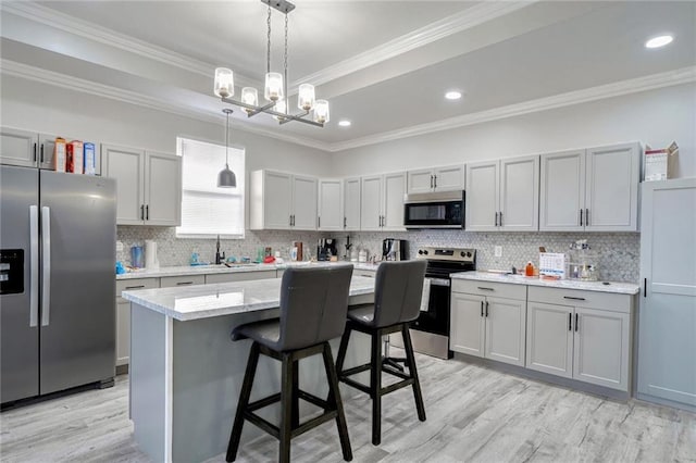 kitchen with light hardwood / wood-style flooring, stainless steel appliances, ornamental molding, and a center island