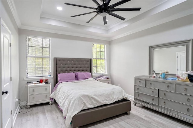 bedroom with ceiling fan, ornamental molding, light wood-type flooring, and a raised ceiling