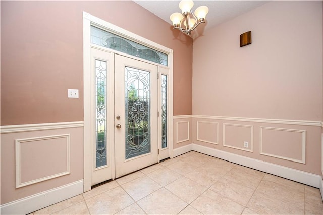 tiled foyer entrance featuring an inviting chandelier