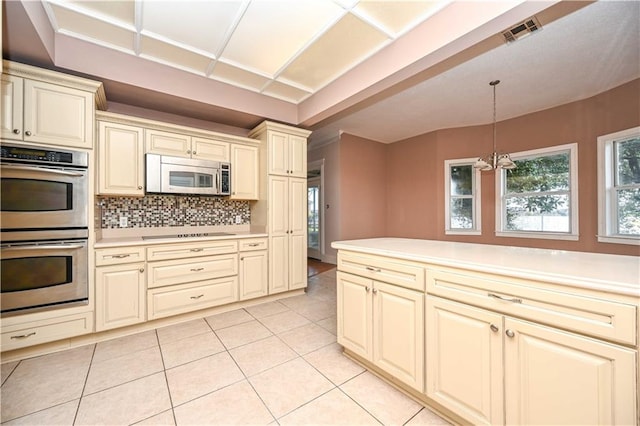 kitchen with pendant lighting, cream cabinets, appliances with stainless steel finishes, and light tile patterned flooring