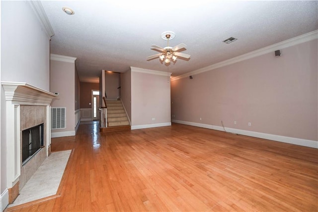 unfurnished living room featuring light wood-type flooring, crown molding, and a tiled fireplace