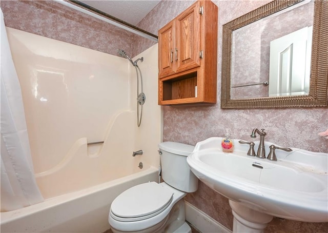 full bathroom featuring a textured ceiling, shower / bath combo, toilet, and sink