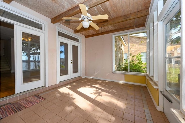 unfurnished sunroom featuring beam ceiling, ceiling fan, wooden ceiling, and french doors