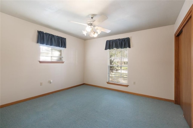 carpeted spare room with ceiling fan and plenty of natural light