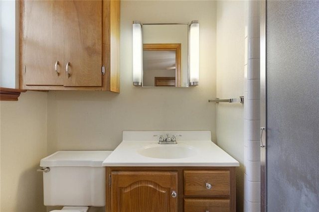 bathroom featuring a shower with shower door, vanity, and toilet