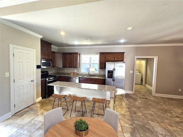 kitchen with a breakfast bar area, stainless steel appliances, sink, a center island, and crown molding