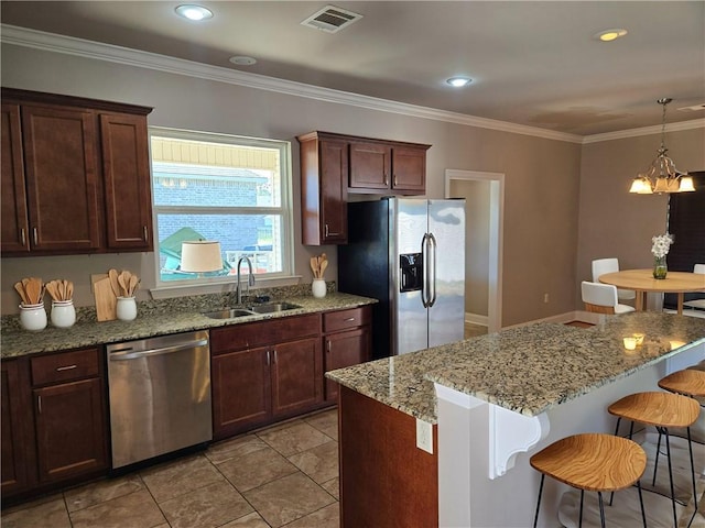 kitchen featuring a breakfast bar area, stainless steel appliances, ornamental molding, sink, and decorative light fixtures