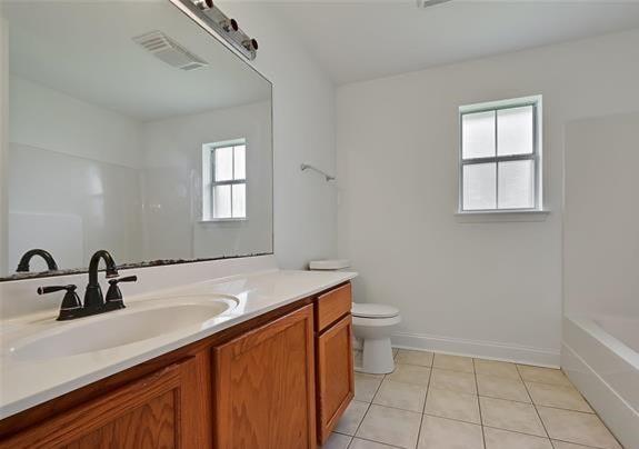 bathroom featuring vanity, tile patterned flooring, toilet, and a healthy amount of sunlight