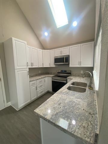 kitchen featuring white cabinets, sink, kitchen peninsula, high vaulted ceiling, and stainless steel appliances