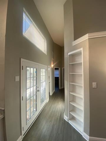 hall with a high ceiling, dark hardwood / wood-style floors, built in features, and french doors