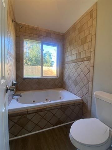 bathroom with hardwood / wood-style floors, toilet, and a relaxing tiled tub