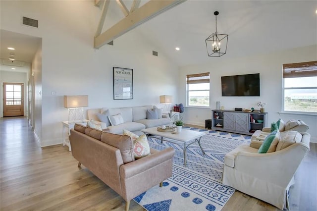 living room with an inviting chandelier, light wood-type flooring, high vaulted ceiling, and a healthy amount of sunlight